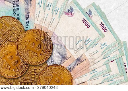 1000 Indonesian Rupiah Bills And Golden Bitcoins. Cryptocurrency Investment Concept. Crypto Mining O