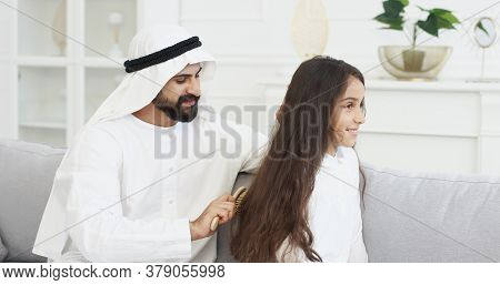 Young Handsome Arab Man In Kandura Talking And Combing Long Hair Of Pretty Small Teen Girl With Comb