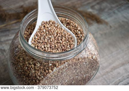 On A Wooden Table There Is A Glass Transparent Jar Filled With Buckwheat Groats