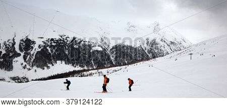 Off-piste Snowy Ski Slope With Skiers In High Mountains And Cloudy Sky At Winter Grey Day. Ski Area 