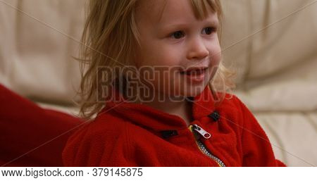 Little baby girl is looking at camera and smilling. She is bored and she trying to sleep. She is covering by blanket.