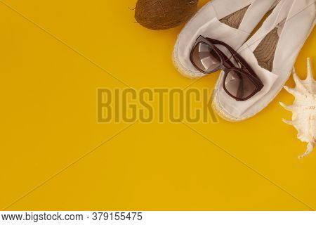 Flat Lay Of Summer And Beach Holiday. Sunglasses, White Espadrilles, Coconut In Yellow Background. C