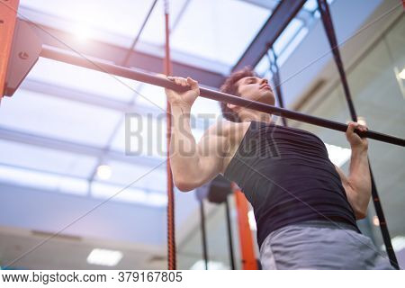 Man doing free body calisthenic pull-ups to traing his back and shoudlers in a gym, fitness and bodybuilding concept