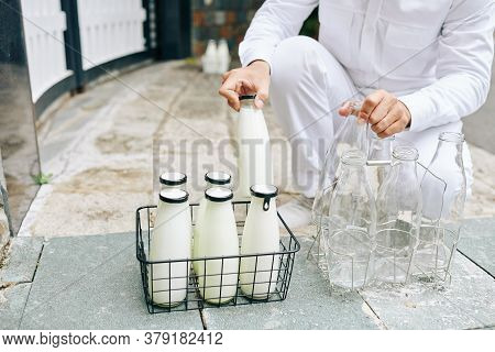 Milkman Putting Glass Milk Bottles In Wire Crane And Taking Back Empty Bottles