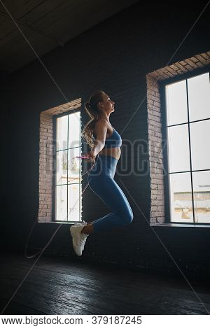 Young Athletic Woman Exercising Using Skipping Rope In Gym