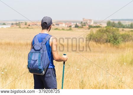 Young Man With Backpack And Sticks Trekking Looking At The Village Of Atapuerca Doing The Camino De 