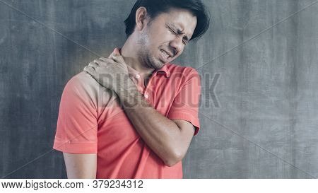 Young Asian Man Suffering From Neck Pain On Cement Wall Background With Copy Space, Problems And Hea