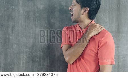 Young Asian Man Suffering From Neck Pain On Cement Wall Background With Copy Space, Problems And Hea