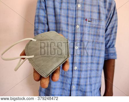 Young Man Offering Or Giving One Grey Color Kn-95 Face Mask. Blue Shirt Guy. Corona Virus Pandemic. 
