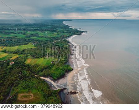 Aerial View Of Coastline With Black Sand Beach, Ocean And Waves In Balian, Bali