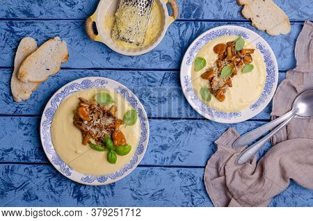Traditional Polenta With Mushrooms And Cheese In A Dish On A Blue Wooden Background. Selective Focus