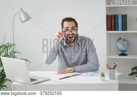 Amazed Young Bearded Business Man In Gray Shirt Glasses Sit At Desk Work On Laptop Pc Computer In Li