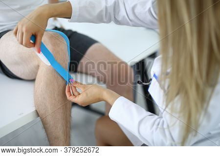 Nurse Should Glue Kinesio Tape On Athletes Injured Knee. Help With Injuries And Sprains For Professi