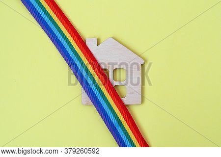 Mini Toy Wooden House And Lgbt Rainbow Ribbbon On Yellow Background, Top View