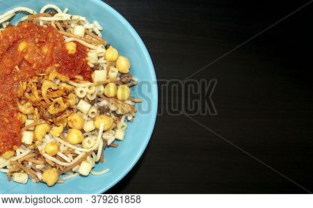Famous Traditional Arabic, Egyptian Dish - Koshari. National Kushari In A Turquoise Plate On Dark Wo
