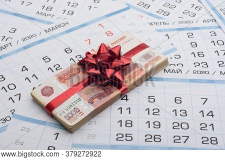 A Bundle Of Russian Five-thousandth Bills With A Red Bow Lies On A Background From A Calendar