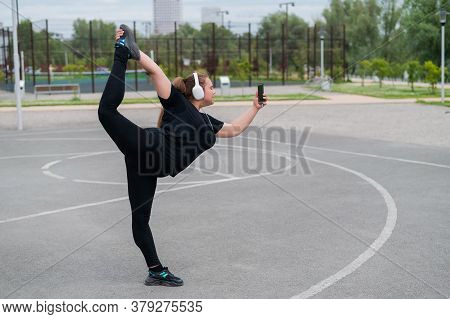 Beautiful Fat Young Woman In Headphones Makes A Figure Skater And Takes A Selfie. A Chubby Smiling G