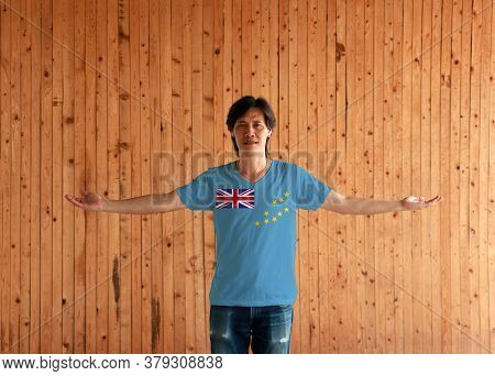 Man Wearing Tuvalu Flag Color Shirt And Standing With Arms Wide Open On The Wooden Wall Background, 