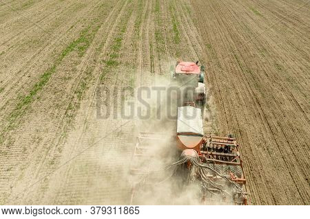 Aerial View. Tractor With Seed Drill Machine Sowing The Seeds For Crops In Spring Season. Beginning 