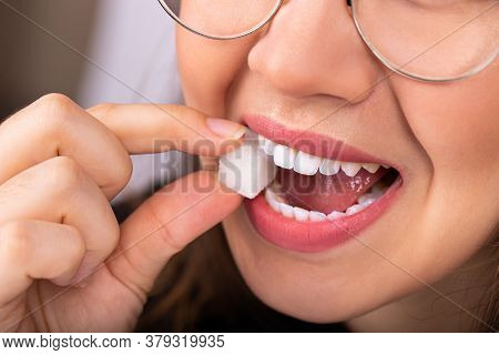Beautiful Woman Mouth With Big White Teeth Bites On A White Sugar Cube