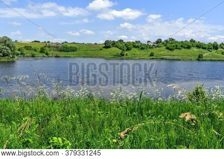 Lake In The Middle Of Meadows With Green Lush Grass On A Sunny Spring-summer Day. Beautiful Rural La