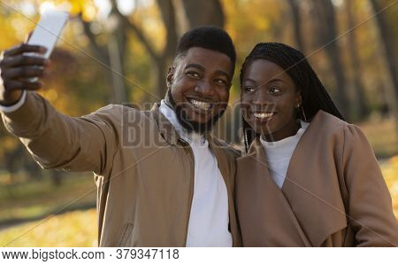 Happy Young Black Man And Woman Taking Self-portrait During Walking In Autumn Park