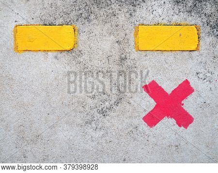 red paint cross marks on cement floor of train station platform with yellow dividing line, symbol for passengers stand to wait for train and keep distance, social distancing concept, close up top view