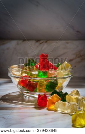 Assorted Flavors Of Gummy Bear Candies In Glass Dish On Marble Kitchen Table
