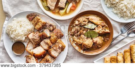 filipino dinner with sinigang, lechon kawali, and chicken adobo top down composition