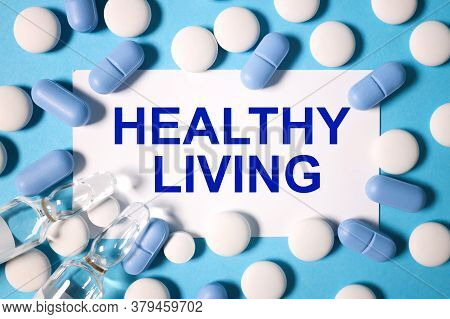 Healthy Living. Text On White Paper On A Blue Background Near Blue And White Pills And A Transparent
