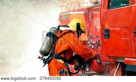 Firefighter Fighting With Flame Using Fire Hose Chemical Water Foam Spray Engine. Fireman Wear Hard