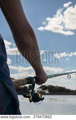 Fishing Rod Wheel Close-up In The Hands Of A Young Man