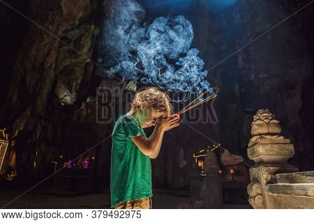 Young Boy Praying In A Buddhist Temple Holding Incense Huyen Khong Cave With Shrines, Marble Mountai