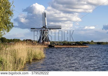 Windmill By The Canal At Glimmen In Holland. Around The Mills Are Excavators And The Background Is A