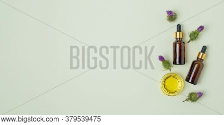 Flat Lay Of Cosmetic Glass Brown Bottles With Dropper, Burdock Flowers And Oil On Mint Background. P