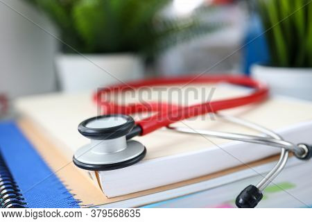 Close-up Of Red Stethoscope Laying On Papers. Instrument To Examine Breath Of Patient. Doctor Office