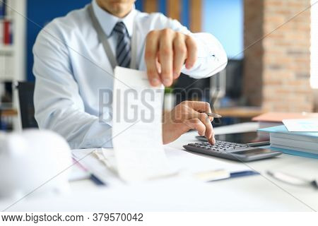 Close-up Of Accountant Specialist Sitting In Office With Calculator And Paper Checks. Man In Present