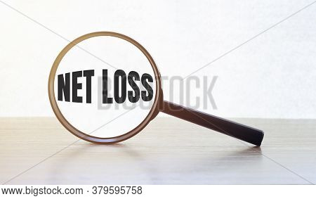 Magnifying Glass With Text Net Loss On Wooden Table.