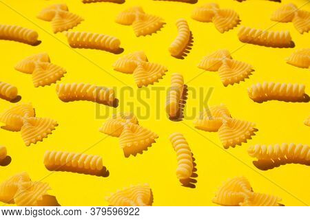 Uncooked Curly Pasta Pattern On Yellow Background. Traditional Dry Raw Macaroni Pattern. Nobody