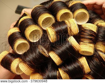 curly woman doing her hair at hairdresser with Velcro rollers
