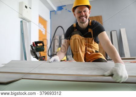 A Carpenter Smiles While Holding A Laminate. Laying Technology With Click Lock. Features Of Sawing L