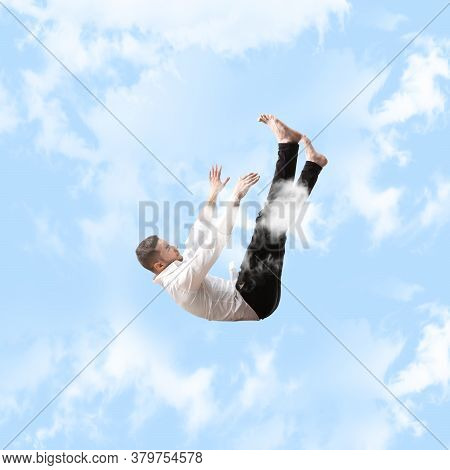 Mid-air Beauty Cought In Sky. Full Length Shot Of Young Man Hovering In Air And Keeping Eyes Closed.