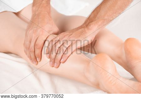 The Masseur Massages The Calf Muscle Of The Girl Lying On The Massage Table. Very Close-up, Soft Lig