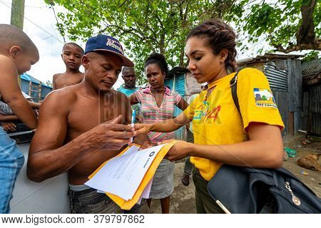 San Cristobal / Dominican Republic - May 16 2018: Brown Woman Signs Some Papers In Front Of A Shirtl