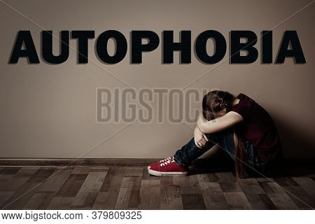 Upset Little Girl Sitting Alone Near Beige Wall. Autophobia - Fear Of Isolation