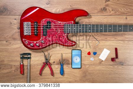 Luthier Table Top View With Bass Guitar And Tools. Craftsman Wooden Desk Flatlay View With Red Elect