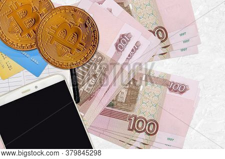 100 Russian Rubles Bills And Golden Bitcoins With Smartphone And Credit Cards. Cryptocurrency Invest