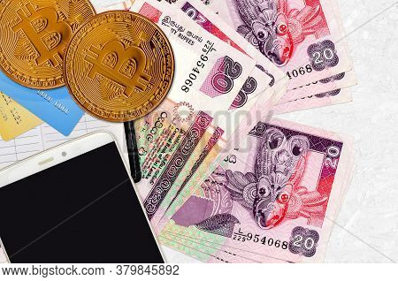 20 Sri Lankan Rupees Bills And Golden Bitcoins With Smartphone And Credit Cards. Cryptocurrency Inve