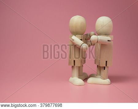 2 Wooden Dolls Hugging Each Other On A Pink Background.
Concept Of Social Contact From Wooden Dolls.