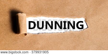 Dunning. Text Is Written On White Paper On Torn Paper Background